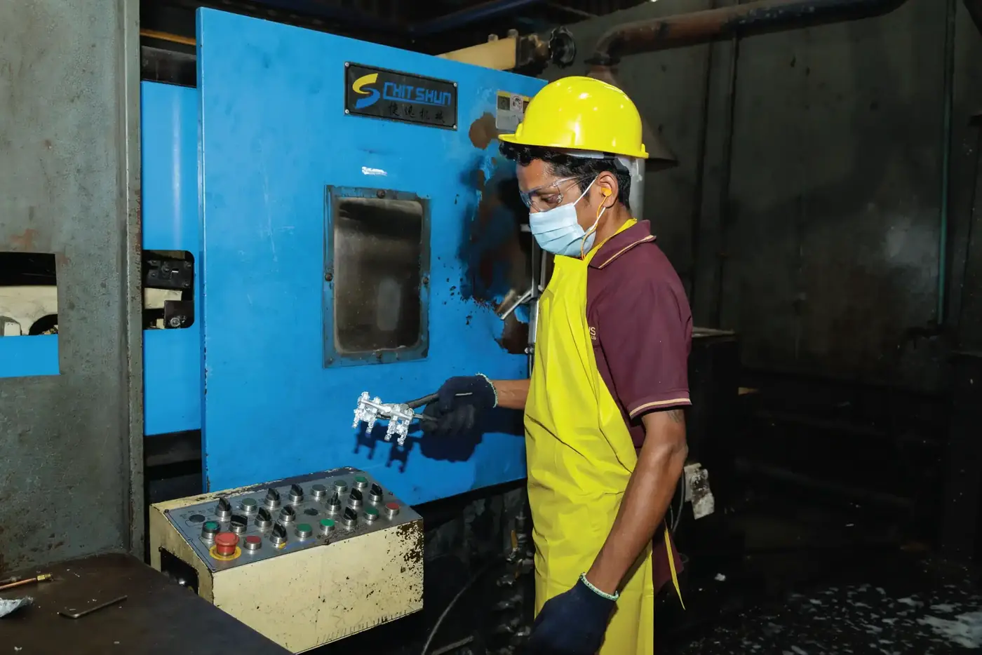 An operator at the die casting machine control panel